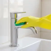 Professional bathroom deep cleaning service showing faucet scrubbing by SKKS expert